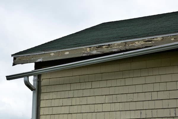 A broken gutter on the side of the house being repaired by centennial colorado roofing pros